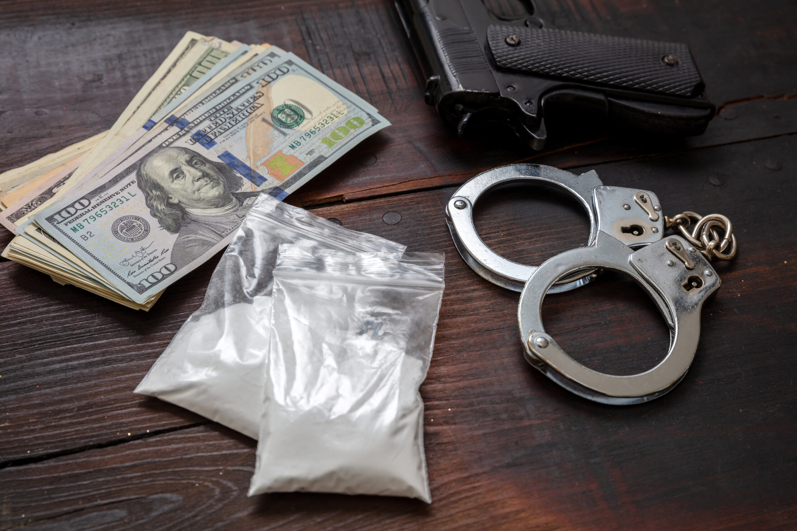 Drugs narcotics possesion and use, arrest and punishment for illegal business concept. Cocaine plastic packets, pistol US dollars and handcuffs.