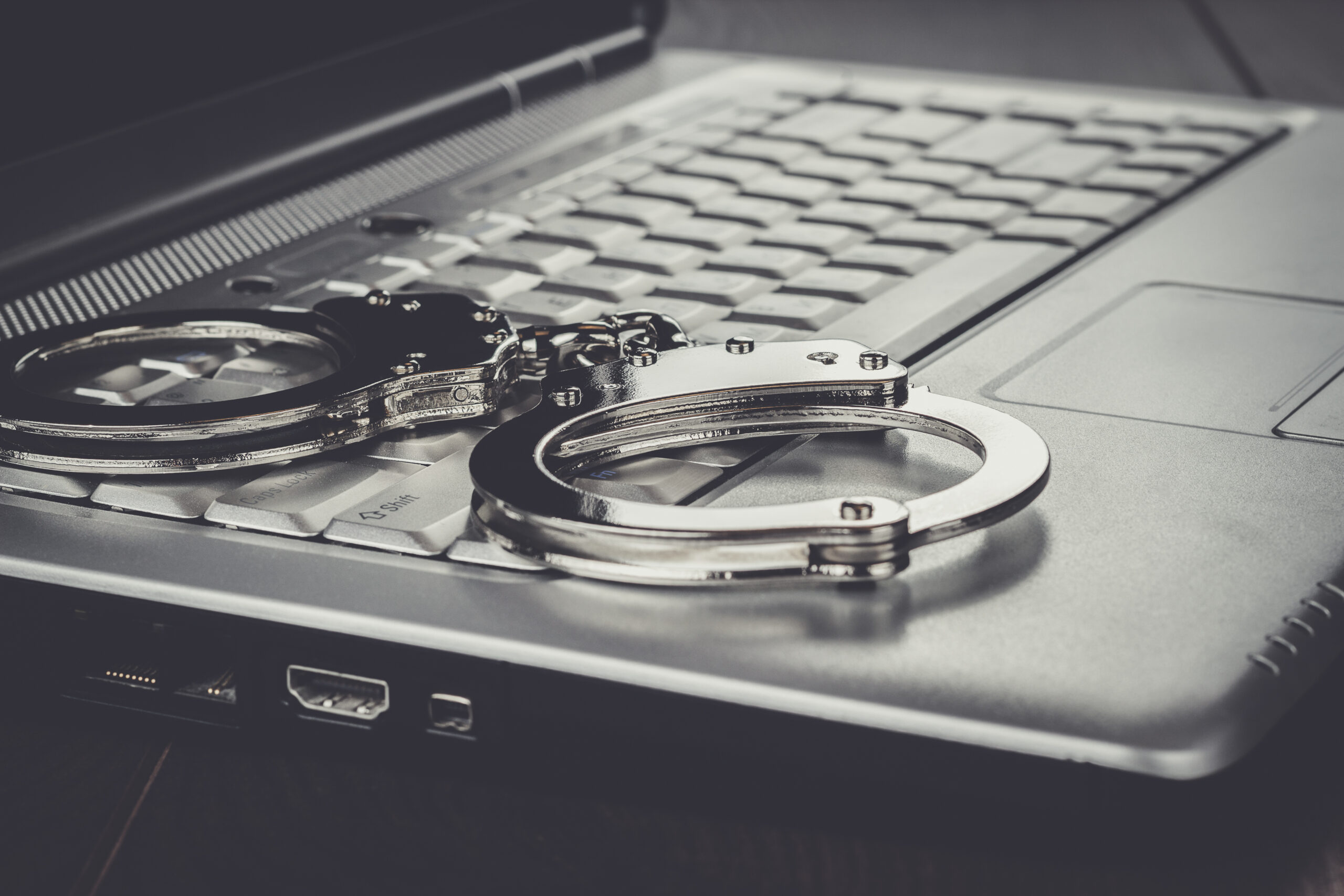 handcuffs on the laptop cyber crime concept for cyber crime lawyers defence in Ontario. 