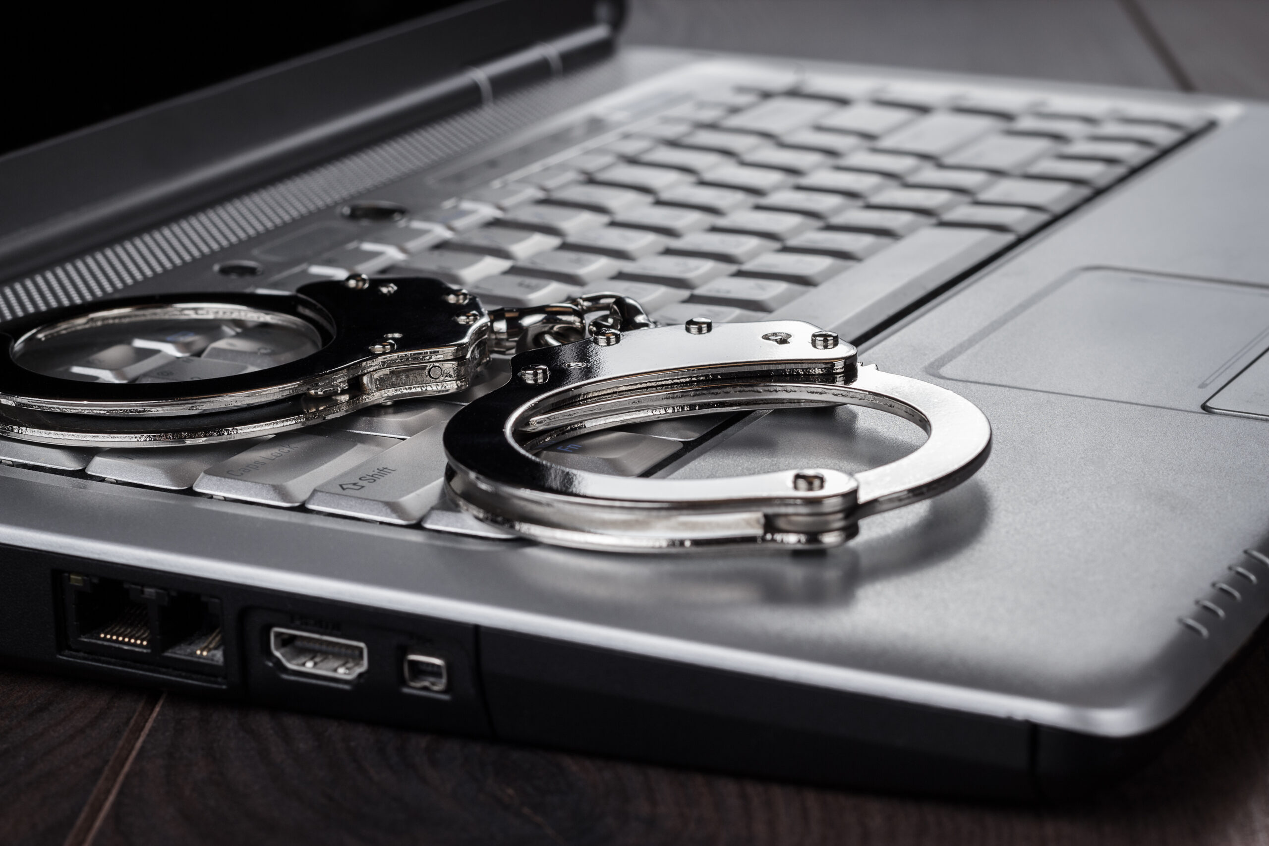 handcuffs on laptop cyber crime concept